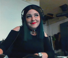 a young woman smiles and flips her hair out of her face. She is facing perpendicular to the camera