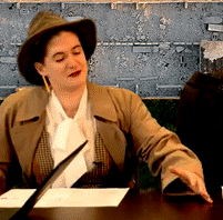 a dark haired person in a fedora and trench coat looks at someone offscreen and asks if their name is Jonomox or judges-alot