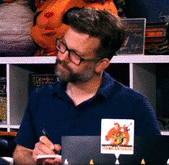 a dark haired man holding a notepad and a pen says make my day in subtitles then raises his pointer finger